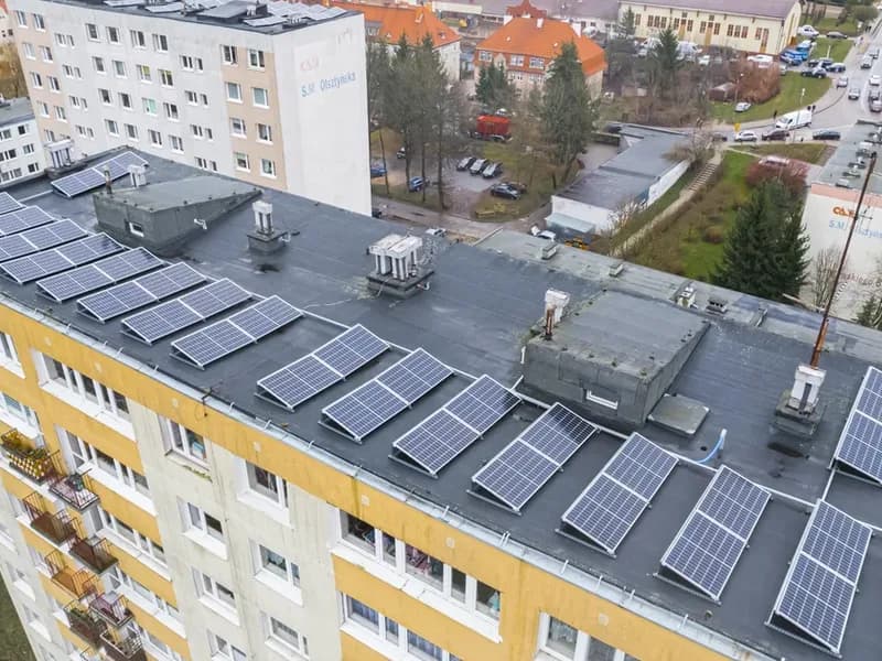 Řady fotovoltaických panelů na ploché střeše panelového bytového domu z ptačí perspektivy
