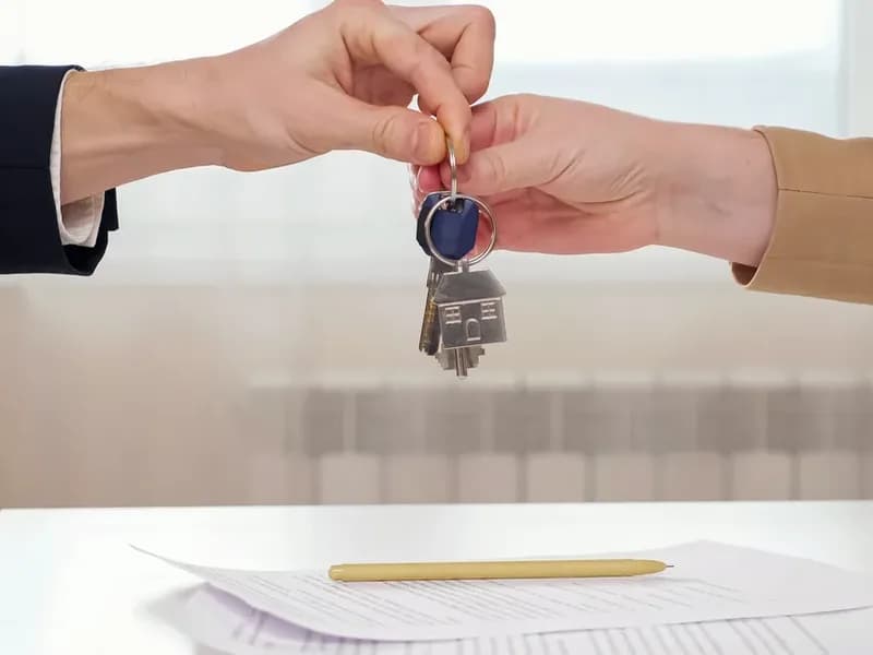 Pronajímatel předává nájemci klíče od bytu nad podepsanou nájemní smlouvou s perem na stole